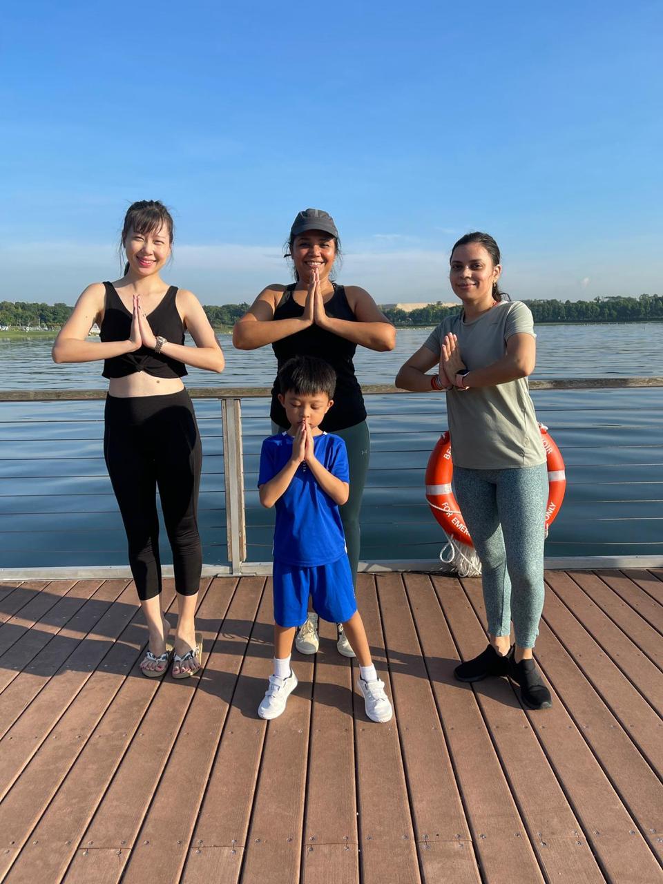 A family group in prayer pose together on a lakeside deck
