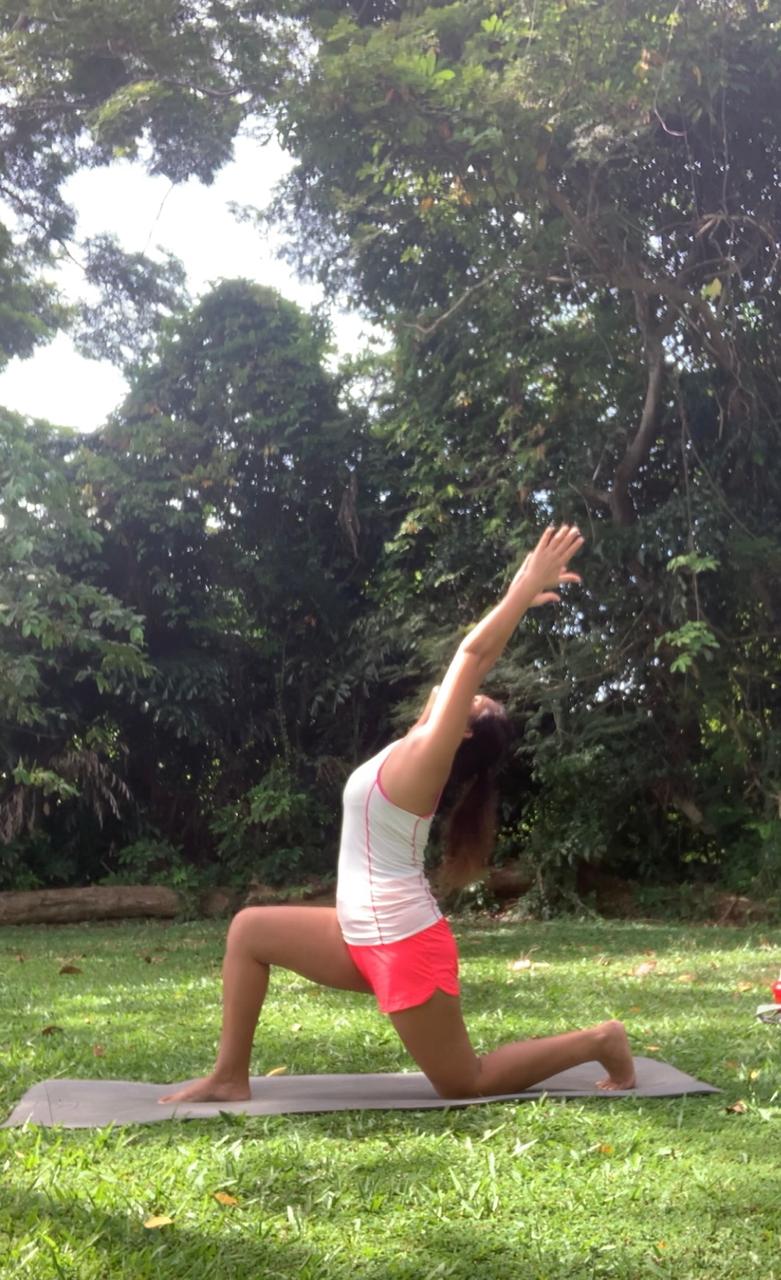 A crescent lunge with arms raised in a green park