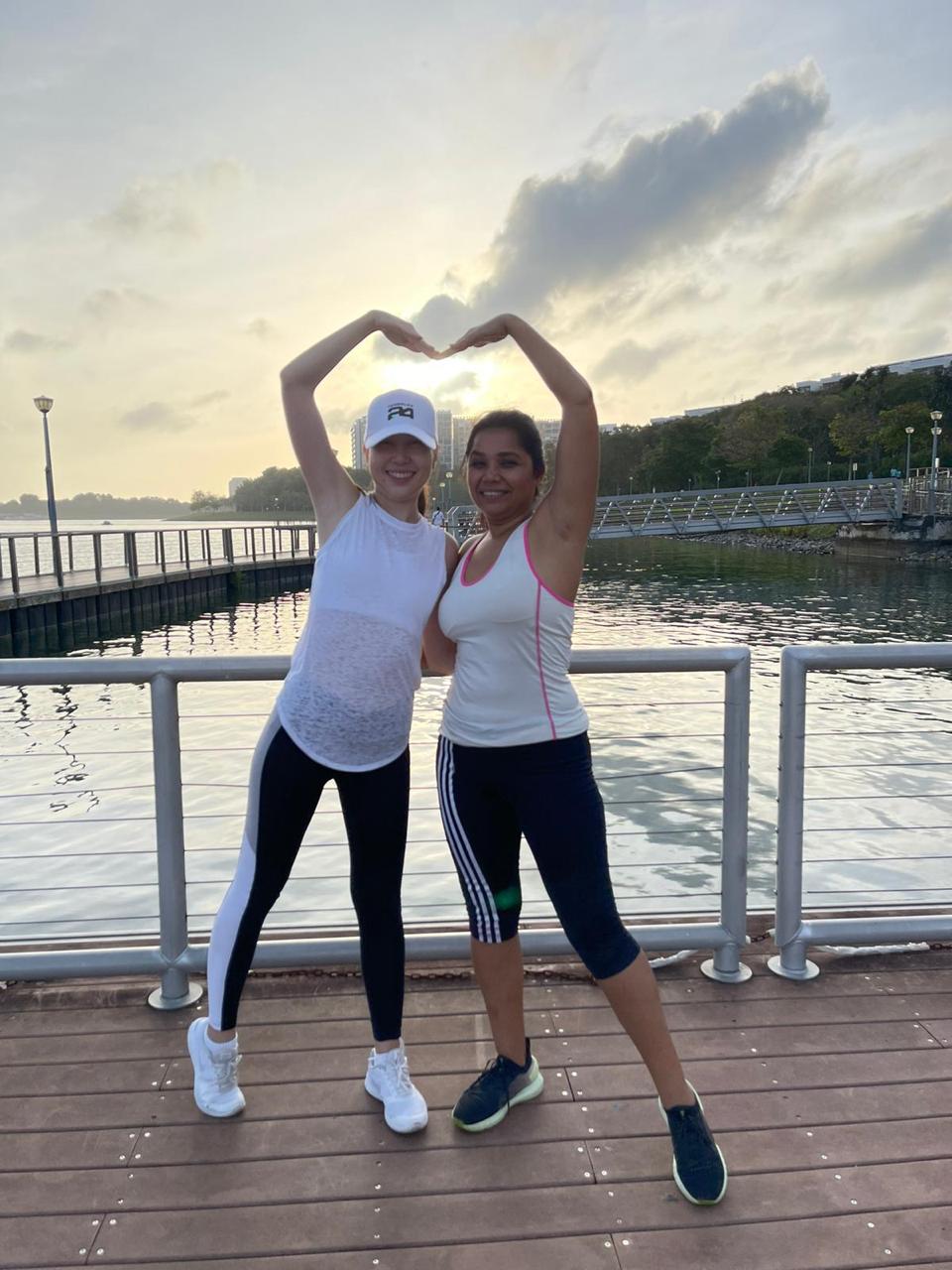 Two practitioners forming a heart shape on a lakeside pier