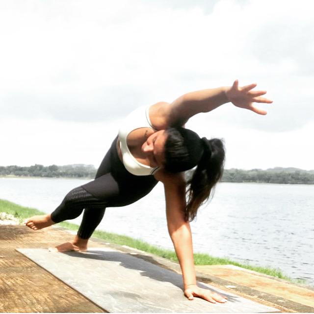 A dynamic side-plank pose beside a calm lake