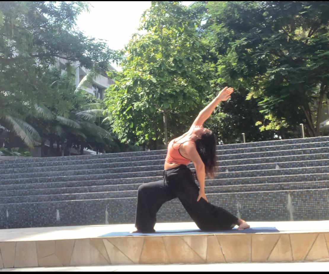 A warrior pose held on stone steps among greenery